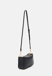 Schwarze Lederhandtasche mit schlankem Design, ausgestattet mit goldenen Hardware-Details und einem langen verstellbaren Tragegurt. Reißverschlussverschluss oben.
