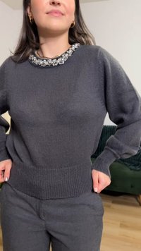 Tmavě šedý oversize pletený svetr s žebrovaným lemem a zdobeným výstřihem s třpytivými akcenty. Měkká textura, volný střih.