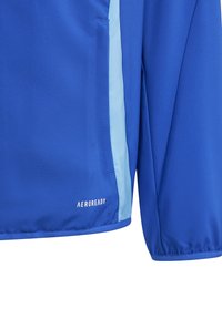Blaues Sportjackett mit glatter Oberfläche, kontrastierenden hellblauen Seitenpaneelen und "AEROREADY" Branding am Saum.