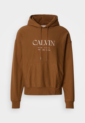 Brun hættetrøje med justerbar snøre i hætten, frontal kængurulomme og hvid tekstlogo med "CALVIN" og "NEW YORK" på brystet.