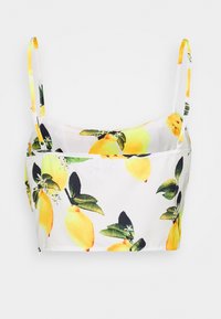 Top de soutien-gorge avec un fond blanc et un motif de citron et de feuilles. Bretelles jaunes ajustables et design ajusté. Texture du tissu lisse.