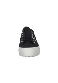 Black canvas sneakers with a white rubber sole, featuring metal eyelets and flat laces. Standard low-top design with a textured outsole.