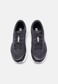 Ζευγάρι μαύρα και άσπρα παπούτσια τρεξίματος Hoka με επάνω μέρος από δίχτυ και κορδόνια, απεικονιζόμενα από πάνω σε λευκό φόντο.