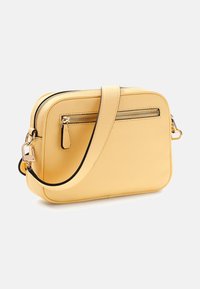 Żółta skórzana torebka na ramię z teksturowanym wykończeniem, z przednią kieszenią na zamek błyskawiczny, złotymi akcentami i regulowanym paskiem.