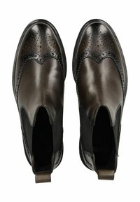 Botas de cuero marrón hasta el tobillo con paneles laterales elásticos, detalles de adorno en forma de brogue y puntera redondeada. Suela de goma negra plana y tira de agarre.