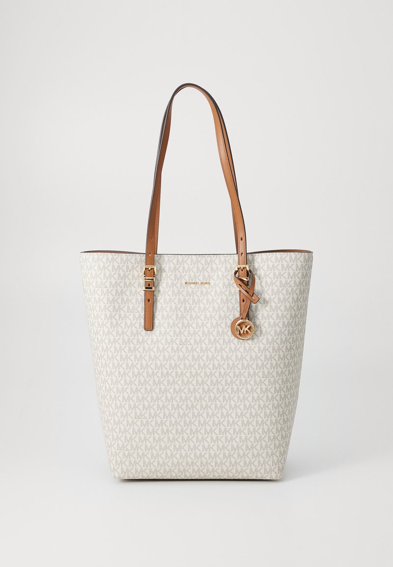 Sac en toile crème clair avec un motif subtil "MK", anses en cuir brun et un pendentif logo doré. Tissu texturé.