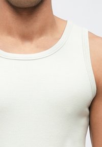 Light gray ribbed tank top featuring a wide neckline and sleeveless design, made of soft cotton material with a smooth texture.