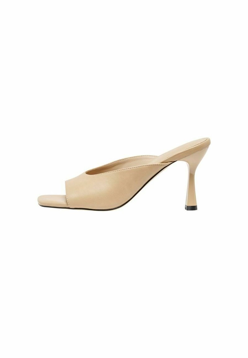 Talons ouverts couleur beige avec une finition en cuir lisse, un talon haut effilé et un accent noir à la base du talon.