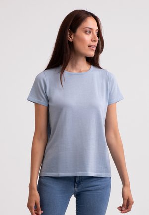 Lichtblauwe katoenen T-shirt met korte mouwen, een ronde halslijn en een relaxte pasvorm, gecombineerd met strakke spijkerbroeken.