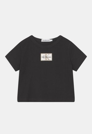 Sort kortærmet crop top med rund hals og lille beige patch-logo med teksten "Calvin Klein Jeans" på brystet.