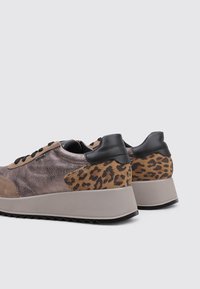 Zapatillas con un upper marrón texturizado, acentos de estampado de leopardo, talón negro y una suela robusta de color gris claro con un patrón estriado.