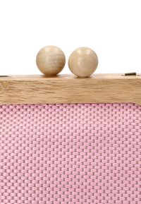 Bolso de mano tejido en rosa con una parte superior de madera, que presenta dos cierres redondos de madera. Textura suave y forma rectangular.