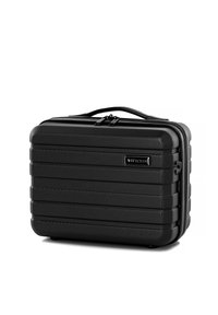Valigia rigida nera con design a coste, chiusura con zip e maniglia superiore. Presenta una placca brandizzata con una texture minimale.