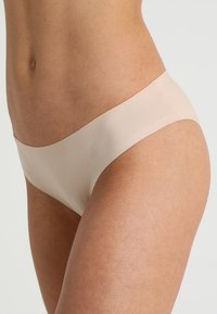 Beige seamless underwear with a low-rise design, featuring a smooth texture and minimalistic style, suitable for everyday wear.