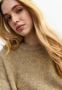 Pullover color marrone chiaro con scollatura a girocollo a costine e una finitura testurizzata, con sottili fili dorati che attraversano il tessuto.