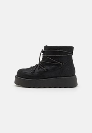 Bottines noires en tissu texturé, avec un bout rond, des lacets réglables et une semelle épaisse à plateforme avec un motif en zigzag.