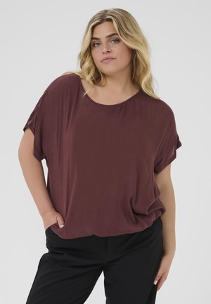 Burgundy loose-fitting blouse with short sleeves, round neckline, and soft texture, paired with black pants. No patterns or hardware.