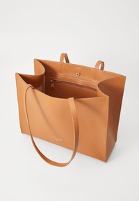 Borsa tote in pelle marrone chiaro con due manici corti, design aperto, tasca interna con zip e logo impressa sul davanti. Texture liscia.