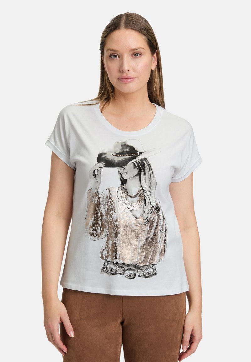 T-shirt blanc à manches courtes avec un graphique représentant une femme portant un chapeau gris et des colliers superposés, avec des détails métalliques sur le t-shirt.