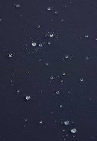 Des gouttes d'eau claires dispersées sur une surface lisse bleu foncé.