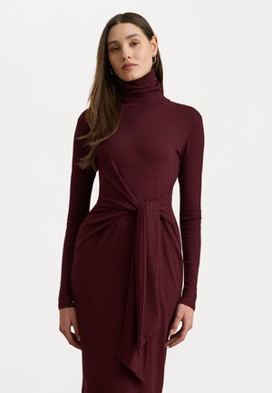 Abito a collo alto bordeaux, maniche lunghe, design aderente, dettaglio in vita con nastro, texture morbida, lunghezza fino al ginocchio, stile minimalista.