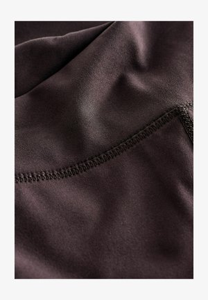 Dunkelbrauner Stoff mit einer glatten Textur, der einen leichten Glanz aufweist und eine detaillierte Naht entlang der Kante zeigt.