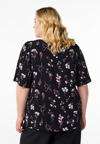 Blusa nera con maniche corte, caratterizzata da motivi floreali colorati in rosa, bianco e blu, realizzata in un materiale leggero con una texture morbida.