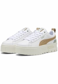 Vita sneakers med en kraftig sula, med en beige mockadel, gröna detaljer och vita snören. PUMA-logotyp på plösen och hälen.