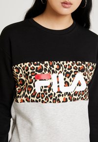 Czarna i szara bluza z panelem w panterkę z czerwonymi akcentami oraz białym logo "FILA" na piersi. Miękka faktura materiału.