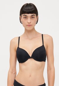 Black padded bra with smooth fabric, underwire support, adjustable thin straps, and a seamless design. No visible patterns or hardware.