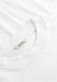 Gros plan sur un t-shirt blanc à col rond montrant l'étiquette de la marque Gabba cousue à l'intérieur du col.