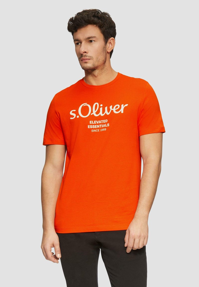 Oranžové bavlněné tričko s kulatým výstřihem, krátkými rukávy a bílým grafickým potiskem "s.Oliver" na přední straně. Hladká textura, ležérní střih.
