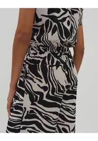 Tissu à motifs zèbre noir et blanc, avec une coupe décontractée, une taille élastique et des poches latérales ; texture lisse.