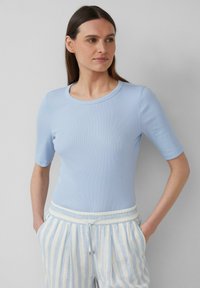T-shirt azzurro chiaro a coste con maniche corte e scollo rotondo, abbinato a pantaloni a righe azzurro chiaro e bianchi con coulisse.