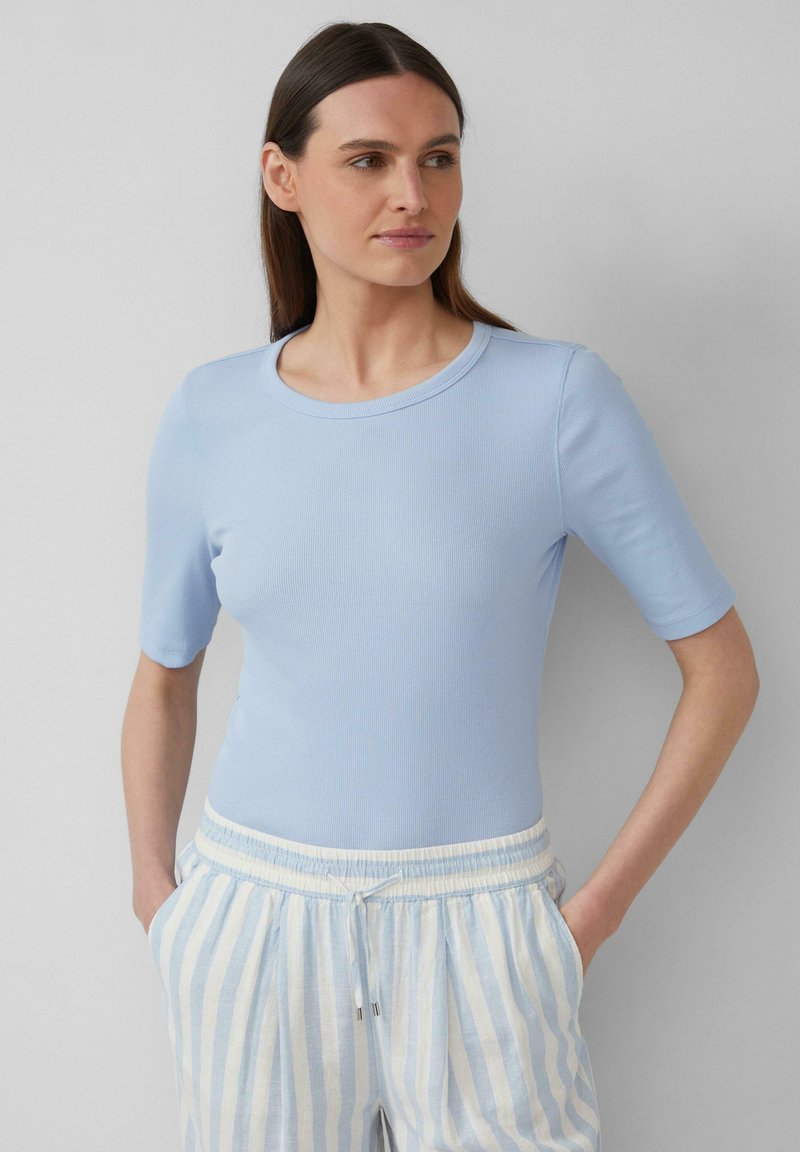 T-shirt azzurro chiaro a coste con maniche corte e scollo rotondo, abbinato a pantaloni a righe azzurro chiaro e bianchi con coulisse.