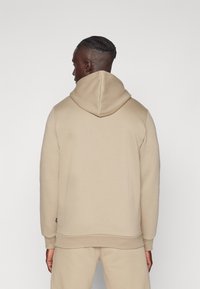 Beige Kapuzenpulli aus weichem Stoff, mit Kordelzugkapuze, langen Ärmeln und gerippten Bündchen. Einfaches Design ohne sichtbare Muster.