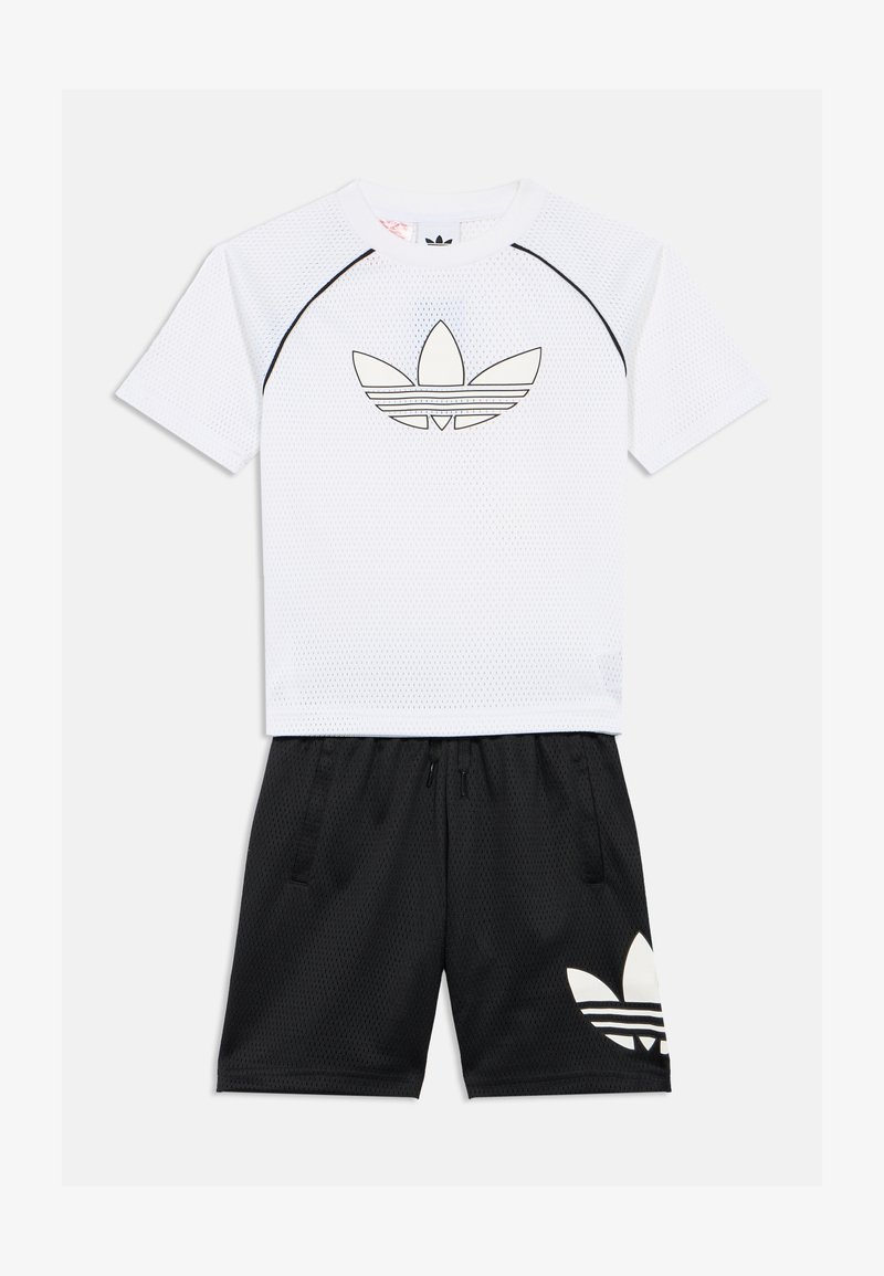 Λευκό κοντομάνικο μπλουζάκι με μαύρες λεπτομέρειες και λογότυπο, συνδυασμένο με μαύρες βερμούδες που διαθέτουν μεγάλο λογότυπο σε λευκό χρώμα. Ελαφρύ σετ αθλητικών ρούχων.