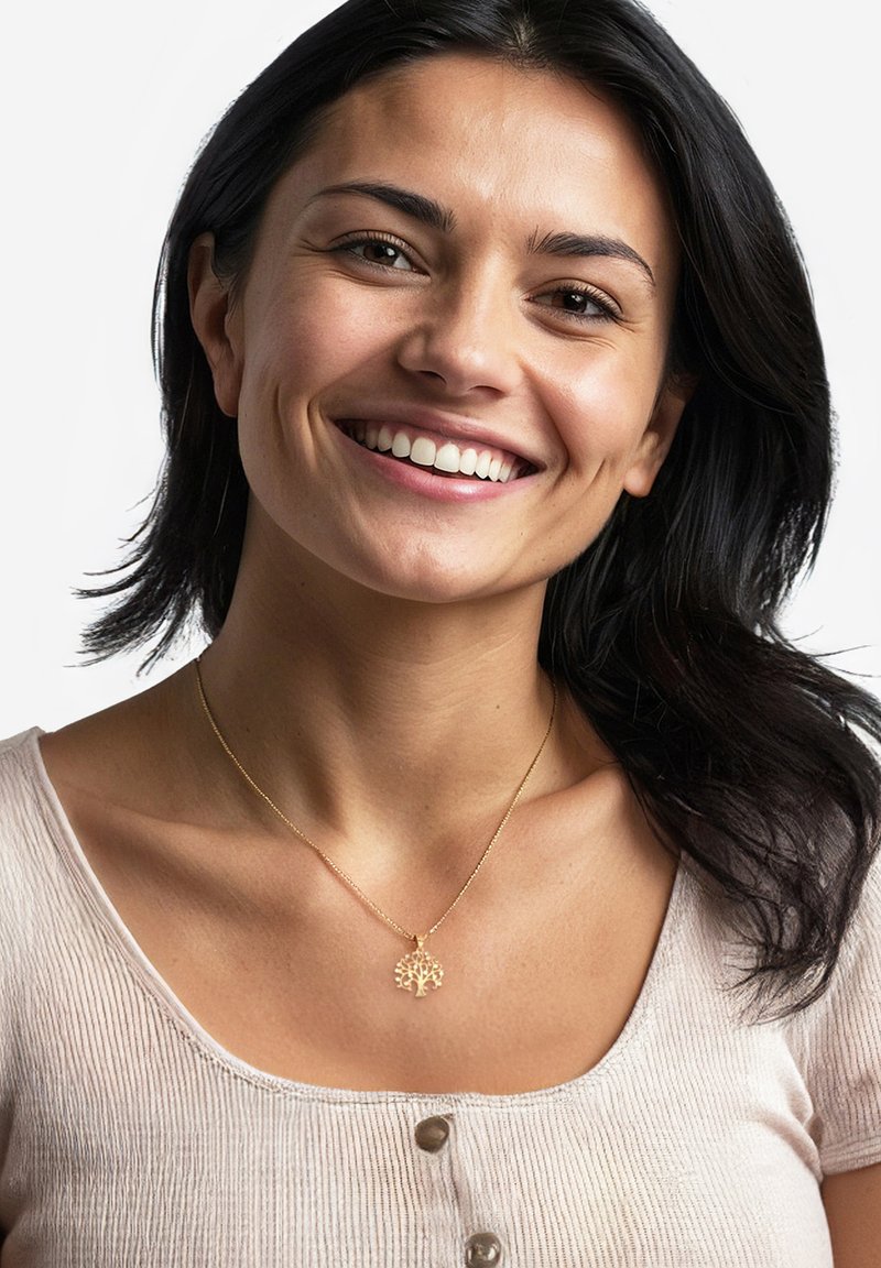 Collana d'oro con pendente a forma di albero della vita, indossata da una persona con capelli scuri, vestita con una maglietta chiara a coste con bottoni.