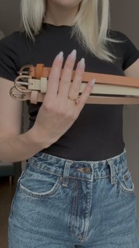 Four leather belts in various colors: brown, light beige, cream, and blush. Each features a gold-tone metal buckle and smooth texture.