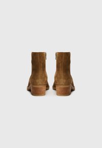 Bottines en daim marron avec un talon en bois empilé. Dotées d'une fermeture éclair sur le côté et d'une texture lisse, conçues pour une utilisation décontractée.
