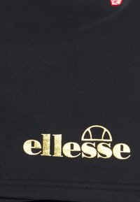 Black cotton t-shirt featuring a gold "ellesse" logo and an emblem with a simple arch design in red above the logo.