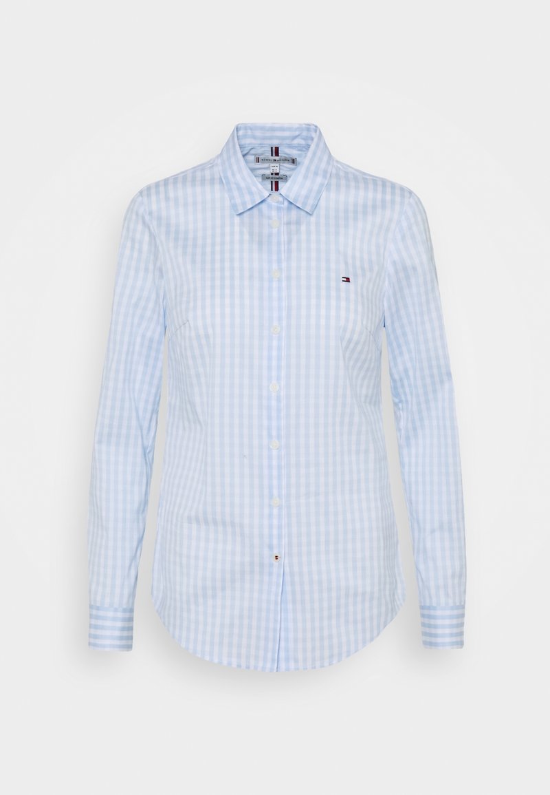 Jasnoniebieska i biała koszula w pionowe paski z długim rękawem, zapinana na guziki, z kołnierzykiem w szpic i małym logo na lewej piersi.