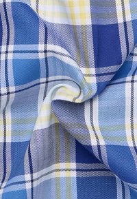 Blauw en geel geruite stof met een mix van strepen en ruiten, met een soepele textuur en een lichte glans, gedrapeerd om diepte te tonen.