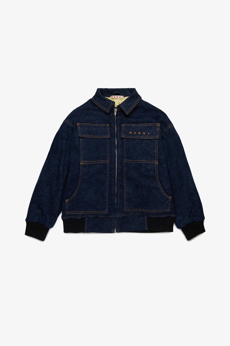 Tamno plavi traper jakna s patentnim zatvaračem, velikim džepovima na prsima, rebrastim manžetama i kontrastnim narančastim šavovima. Ima stajleski ovratnik.