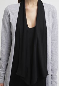 Grauer Langarm-Cardigan mit einem drapierten schwarzen Schal. Der Cardigan hat eine weiche Textur, ein offenes Frontdesign und eine lockere Passform.