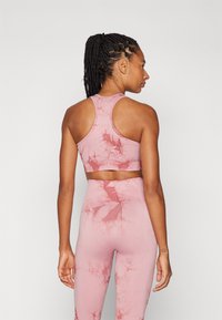 Lys rosa sports-BH og tights-sett med et subtilt marmorert mønster, laget av elastisk materiale. Har en racerback-design.