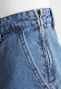 Světle modré džíny s vysokým pasem, se zipovým zapínáním, jemnými švy a klasickým pětivreckovým designem.