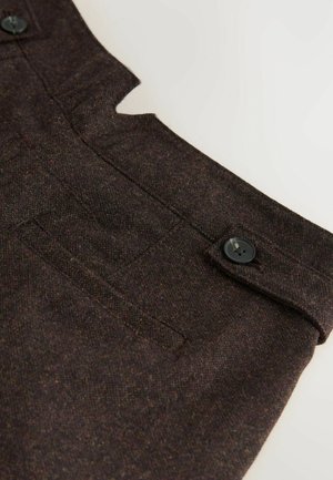 Donkerbruine wollen broek met een taillebandsectie, voorzien van een knoopsluiting en een klein horizontaal zakje op een lichte achtergrond.