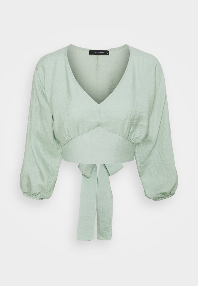 Lys grøn cropped bluse med V-hals, oppustede trekvartærmer og en frontbinding ved taljen.