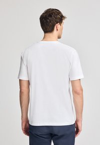 Vit bomull t-shirt med korta ärmar och rundad halsringning. Enkelt design, slät textur, inga synliga mönster eller detaljer.